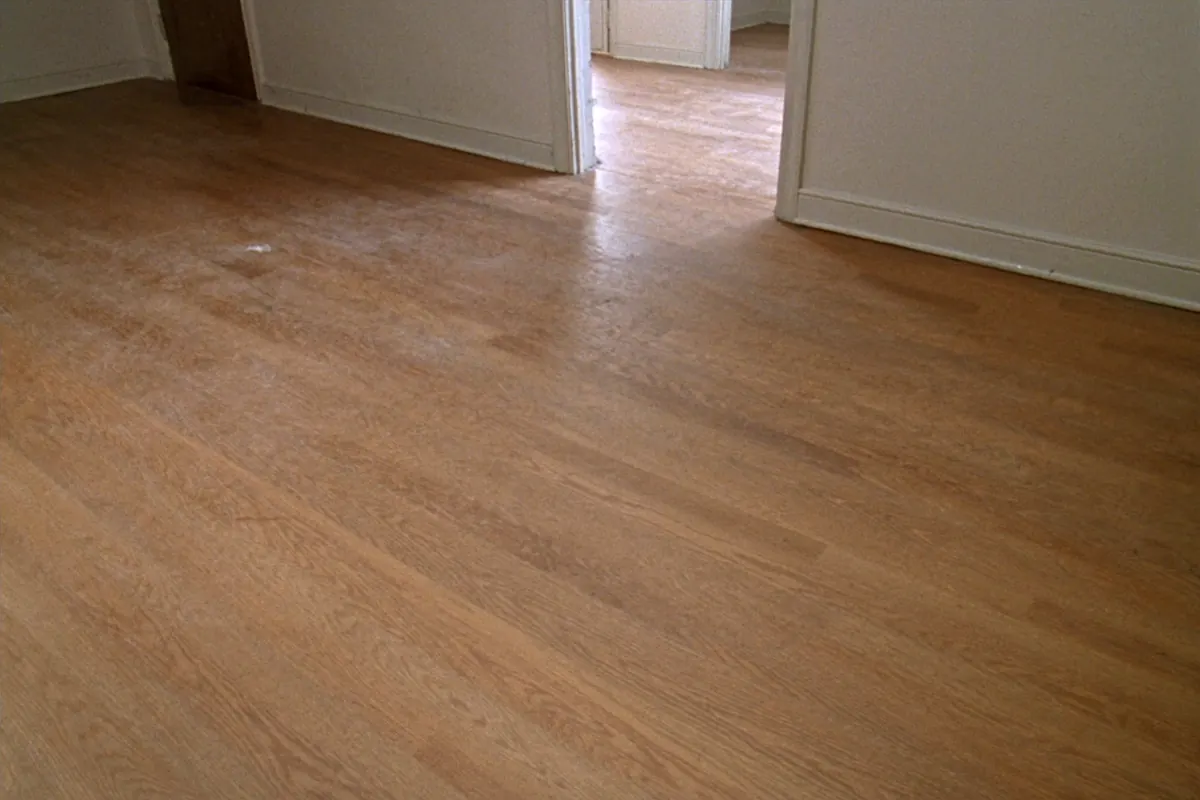 A hallway floor whose finish has gone dull and cloudy, with no bare wood showing